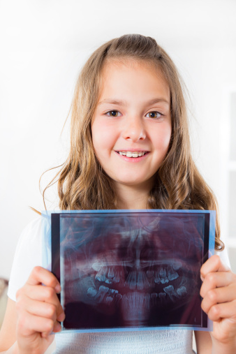 Young girl with dental braces showing x-ray of teeth for orthodontic emergency