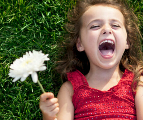 A young girl holding a flower and smiling
