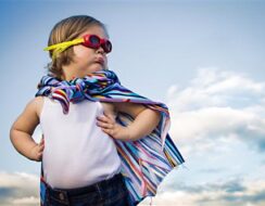 A child in a superhero pose with a cape