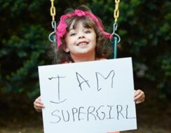 super girl needs braces orthodontist holding sign.